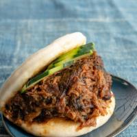 Pulled Pork Bao · Six hours braised pulled pork with preserved vegetable on open steamed bun, garnished with c...