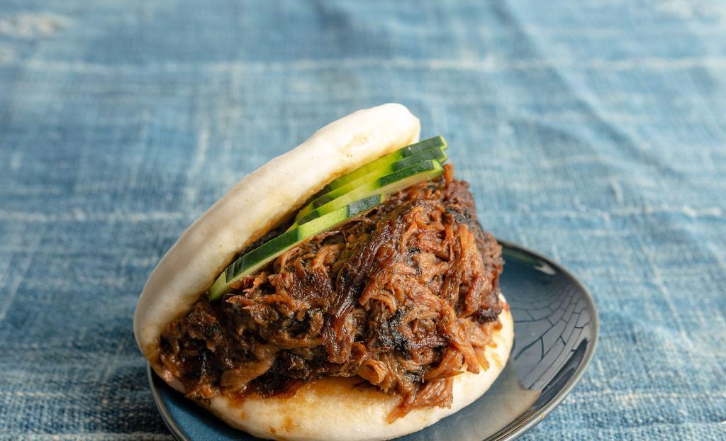 Pulled Pork Bao · Six hours braised pulled pork with preserved vegetable on open steamed bun, garnished with cucumber.
