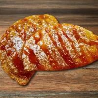 Apple Pie Empanada · Gooey Apple Pie filled Empanada deep fried and topped with rich caramel and powdered sugar