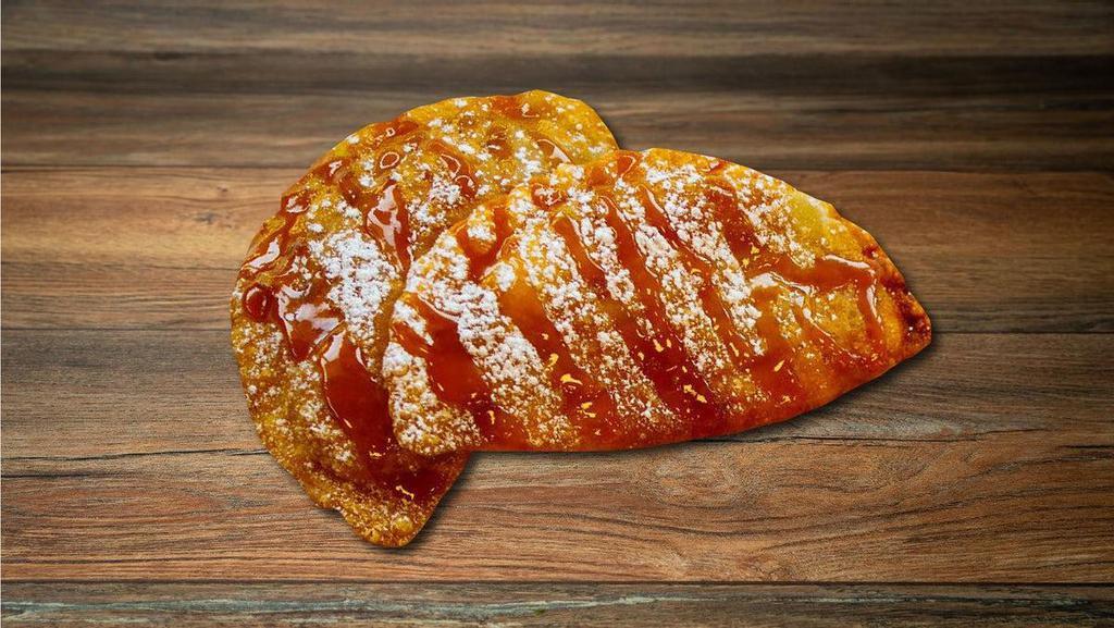 Apple Pie Empanada · Gooey Apple Pie filled Empanada deep fried and topped with rich caramel and powdered sugar