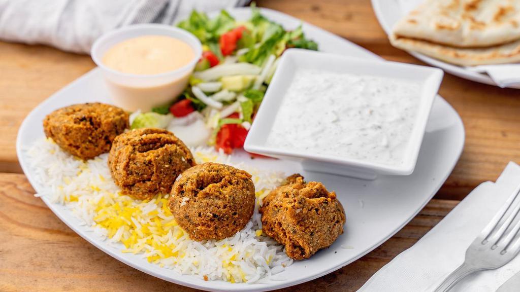 Falafel Platter · Crispy falafels served over rice with a side of salad, house-made white sauce, and spicy sauce.
