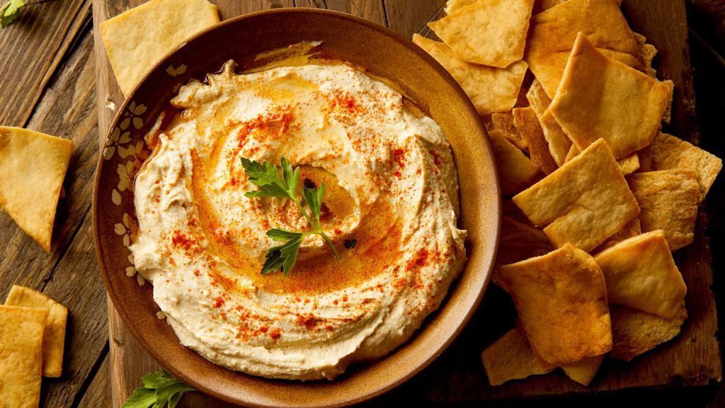 Hummus With Pita Bread · Traditional chickpea dip prepared with olive oil, freshly squeezed lemon juice, tahini, and chopped garlic served with warm pita bread.
