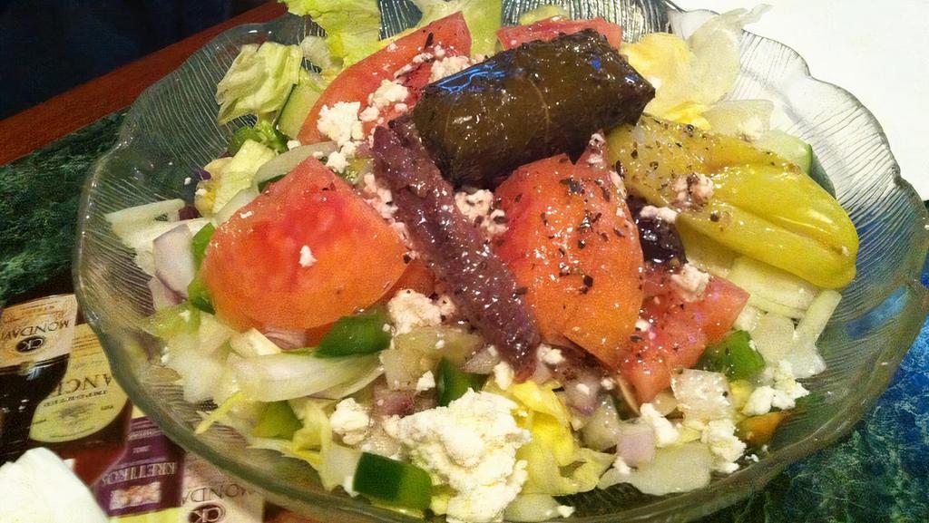 Greek Salad · Lettuce, pepperoncini, stuffed grape leaves, tomatoes, Greek olives, feta cheese, cucumbers, anchovies, and Greek dressing.