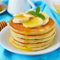 Banana Pancakes · Stack of fluffy banana packed pancakes served with butter and syrup.