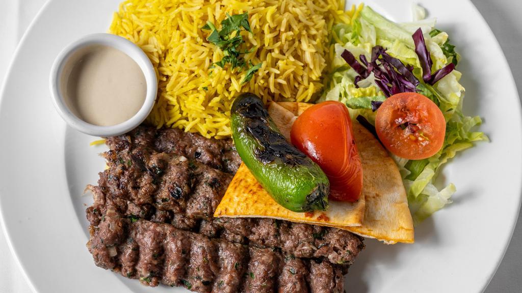 Kofta Kebab · Four skewers of grilled seasoned ground meat with rice.