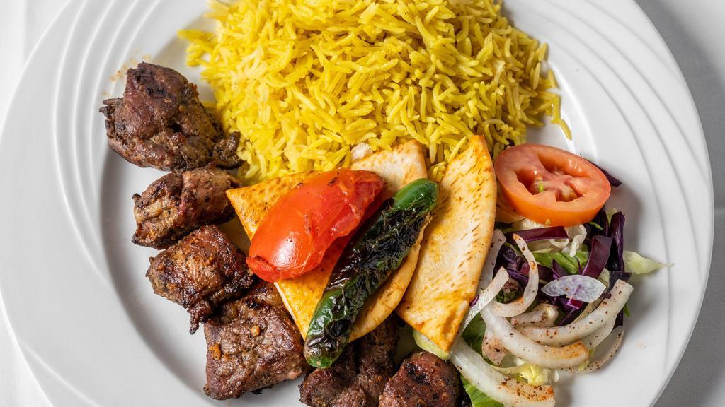 Lamb Shish Kebab · Two skewers of grilled marinated meat cubes with rice.