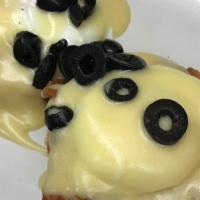 Eggs Blackstone · 2 poached eggs on an english muffin with tomatoes bacon and olives topped with hollandaise s...