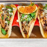 Carnitas Tacos · Slow smoked and shredded pork served with salsa verde, cotija cheese, onions & cilantro on o...