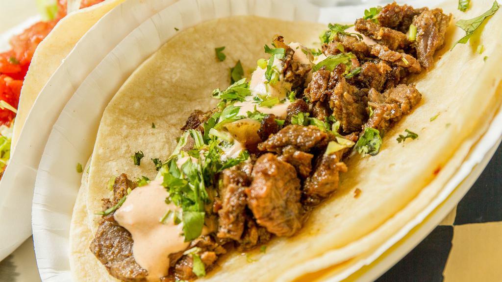 Carne Asada Soft Taco · Marinated steak, sauteed onions, cilantro, chipotle lime sour cream. All topped with onions and cilantro, on corn tortillas.