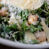Kale Caesar Salad · Shaved aged parmesan crisp and crispy kale, tossed in a creamy caesar dressing topped with c...