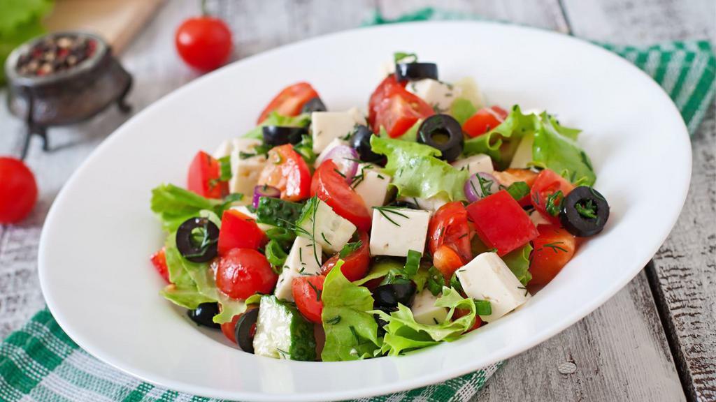 Greek Salad · Fresh salad made with romaine lettuce, feta cheese, stuffed grape leaves, tomatoes, red onions, Kalamata olives, cucumbers, and bell peppers.