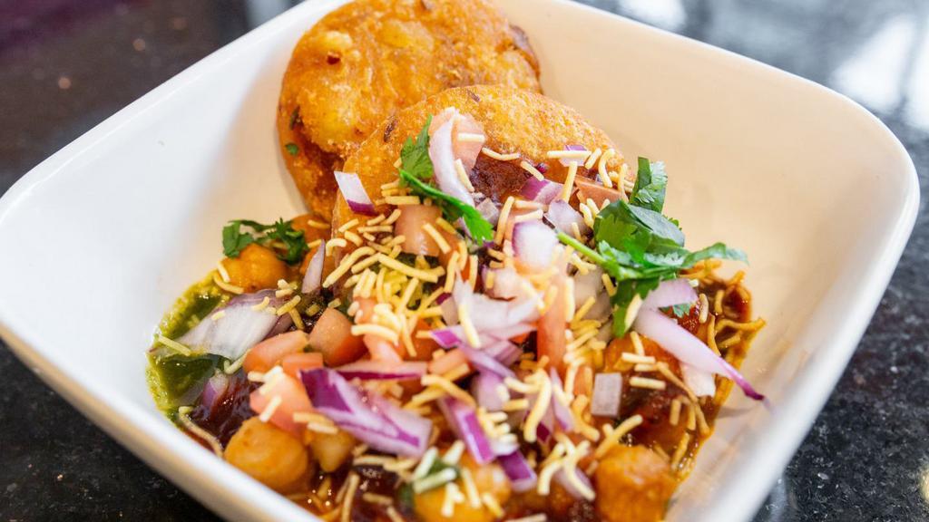 Aloo Tikki Chole · potato cakes topped with chickpeas, garnished with spiced yogurt, mint & tamarind chutney.