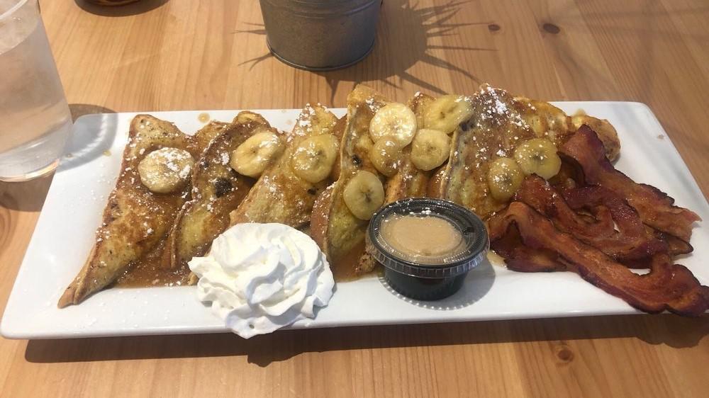 Bananas Foster French Toast · Thick sliced french toast topped with caramelized bananas, whipped cream and served with homemade maple butter and your choice of meat.