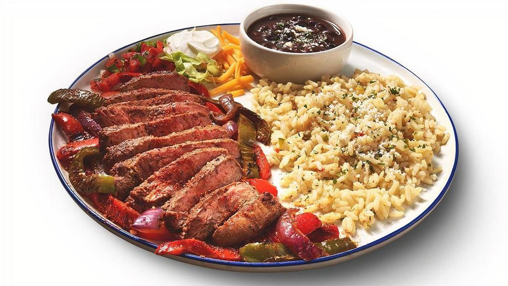 New! Steak Fajitas · Grilled steak seasoned with our special blend of Mexican spices.  Served on a bed of grilled peppers & onions, with rice, seasoned black beans, shredded lettuce, sour cream, pico de gallo, cheddar cheese, and flour tortillas