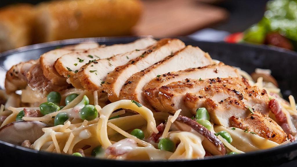 Chicken Carbonara · Grilled chicken served atop fettuccine tossed with Parmesan cream, bacon, peas, roasted baby bellas, and Parmesan cheese.  Served with 4 Breadsticks.