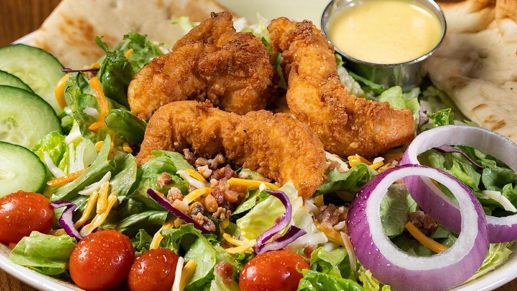 Crispy Honey Mustard Chicken Salad · Hand-breaded crispy chicken tenders on a bed of fresh mixed greens. Topped with applewood smoked bacon, Monterey Jack and cheddar cheeses, tomatoes, cucumbers and red onions. Served with warm flatbread and dressing on the side.