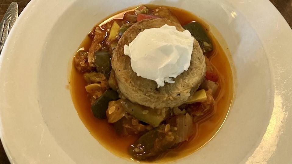 Oeuf Gamin · Poached egg in a mixed herbs potato goat cheese nest on a bed of thick slow cooked ratatouille.