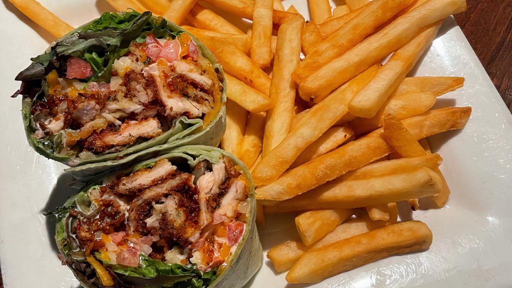 The Wrangler Wrap · Crispy chicken, bacon, shredded cheddar-jack cheese, lettuce, tomato & ranch dressing in a spinach wrap & comes with your choice of a side