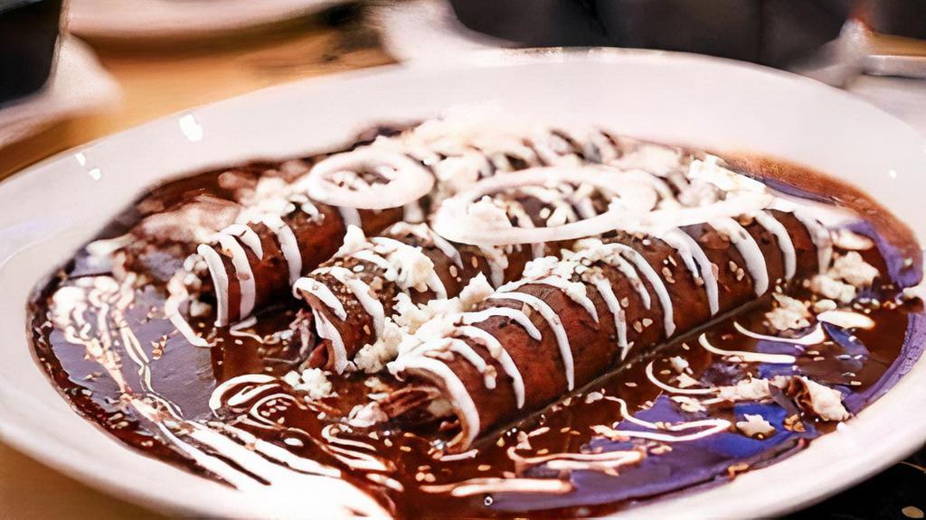 Enchiladas De Mole Poblano · 3 soft corn tortillas rolled and filled with choice of protein. Topped with signature mexican mole poblano sauce and crema fresca. Side of rice and beans