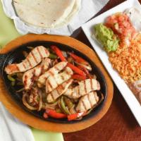 Fajitas · Served on a bed of mixed vegetables with flour tortillas, side dish of guac, refried beans, ...