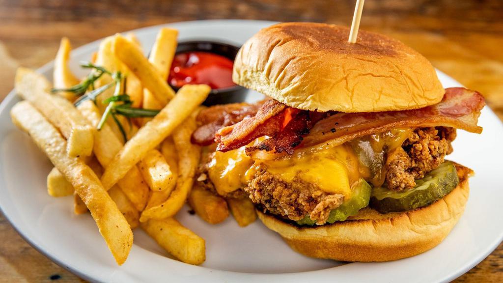 Clara'S Chicken Sandwich · Buttermilk brined Coleman's organic chicken thigh topped with cheddar cheese, applewood cold smoked bacon and pickles on a butter toasted potato roll. Served with fries.