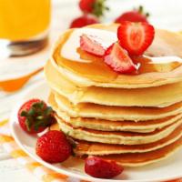 Strawberry Pancakes · Three fluffy, delicious pancakes with fresh strawberries, served with butter and syrup on th...