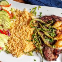 Rib Eye Steak · Served with rice, salad with avocado and scallion onions.