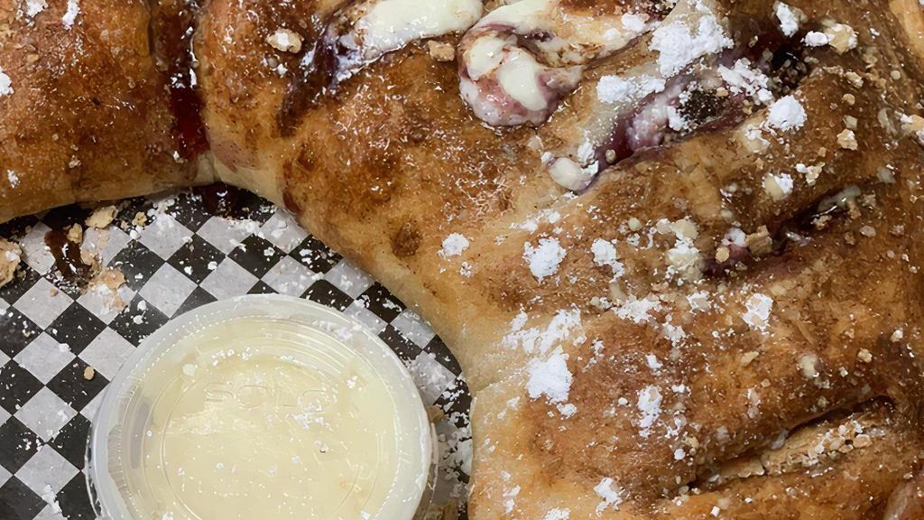 Blueberry Cheescake Calzone · Folded dough filled with cheesecake filling, blueberry pie filling and graham crackers, topped with cinnamon butter and graham cracker crumbles