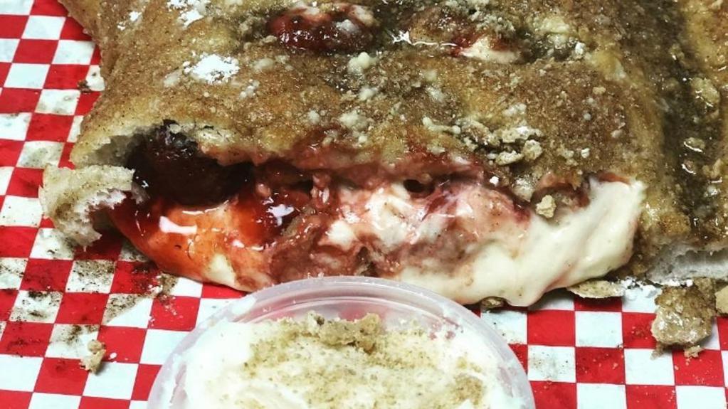 Cherry Cheesecake Calzone · Folded dough filled with cheesecake filling, graham crackers and cherry pie filling. Topped with cinnamon butter and graham cracker crumbles