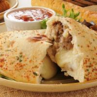 Philly Cheese Calzone · Golden calzone prepared with steak, fresh onion, green peppers, American cheese, and baked t...