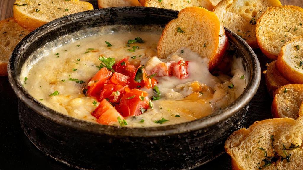 Spinach & Artichoke Dip · A housemade blend of creamy spinach and artichokes topped with seasoned diced tomatoes. Served hot with freshly baked garlic baguette slices.