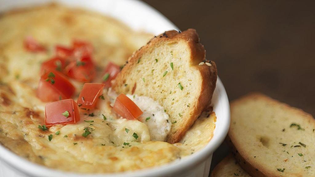 Shrimp & Crab Dip · A creamy shrimp, crab, and parmesan dip baked and topped with diced fresh tomatoes. Served with freshly baked garlic baguette slices.