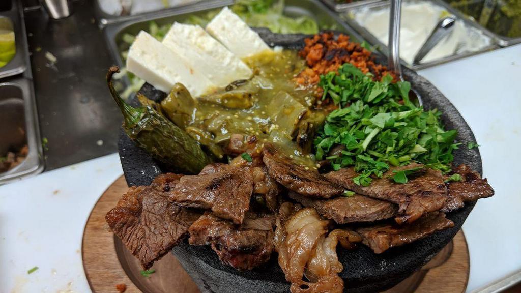 Molcajete · A traditional Mexican dish with grilled chicken breast, rib-eye steak, shrimp, Mexican sausage, grilled jalapeño, onions, bell pepper, grilled nopales (cactus) and queso fresco topped with our homemade sauce served with Mexican rice, beans and your choice of corn or flour tortillas.