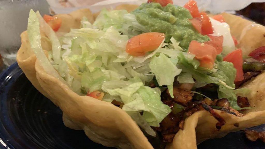 Fajita Taco Salad · Our delicious taco salad served with fajita-style chicken or steak with grilled bell peppers and onions, lettuce, tomatoes and guacamole.
