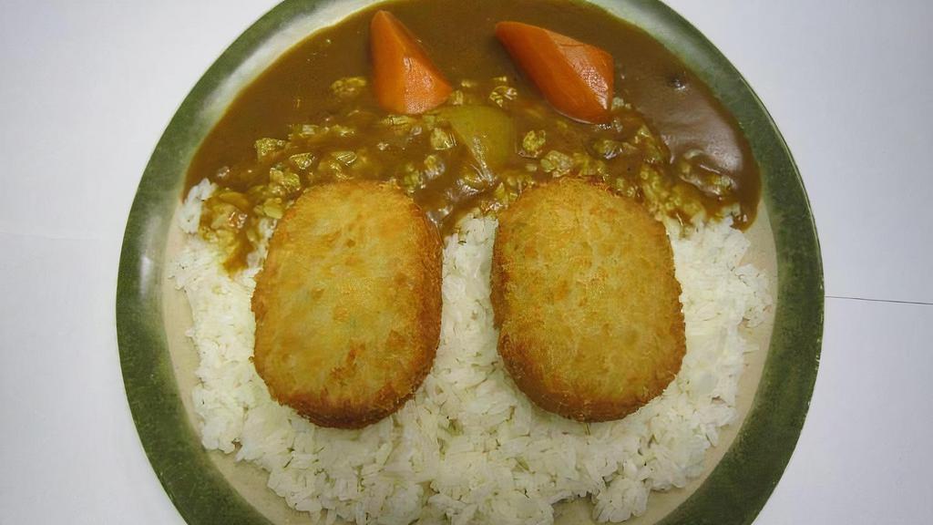Vegetable Croquette Curry · Vegetable croquette with golden curry sauce on white rice.
