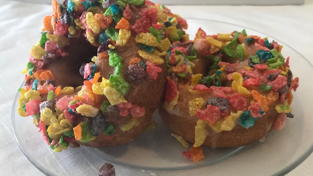 Cereal Killer · Vanilla cake dipped in honey glaze glaze topped with fruity pebbles.