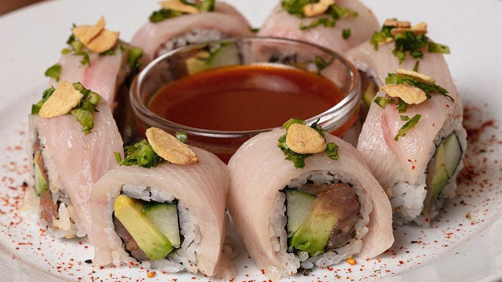 Chili Ponzu Yellowtail Roll · Spicy yellowtail mix rolled with cucumber, avocado, jalapeños and cilantro; topped with yellowtail, green onions, crispy garlic and togarashi; served with chili ponzu sauce.