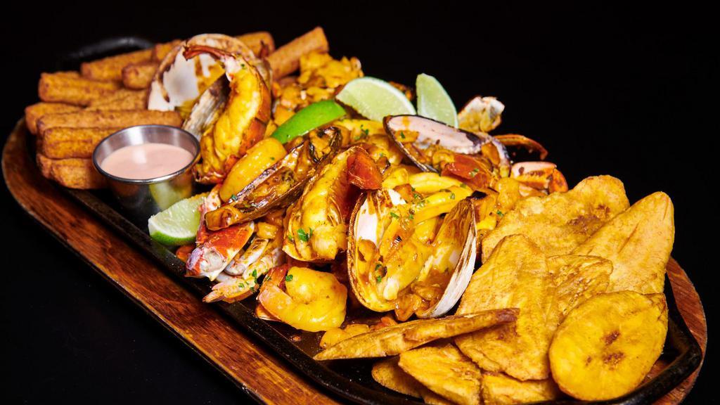 Parrillada De Mariscos · Grilled Seafood Platter: Langosta, Calamares, Camarones, Mejillones. Almejas y Pasta de Cangrejo con Tostones y Yuca Fritas
