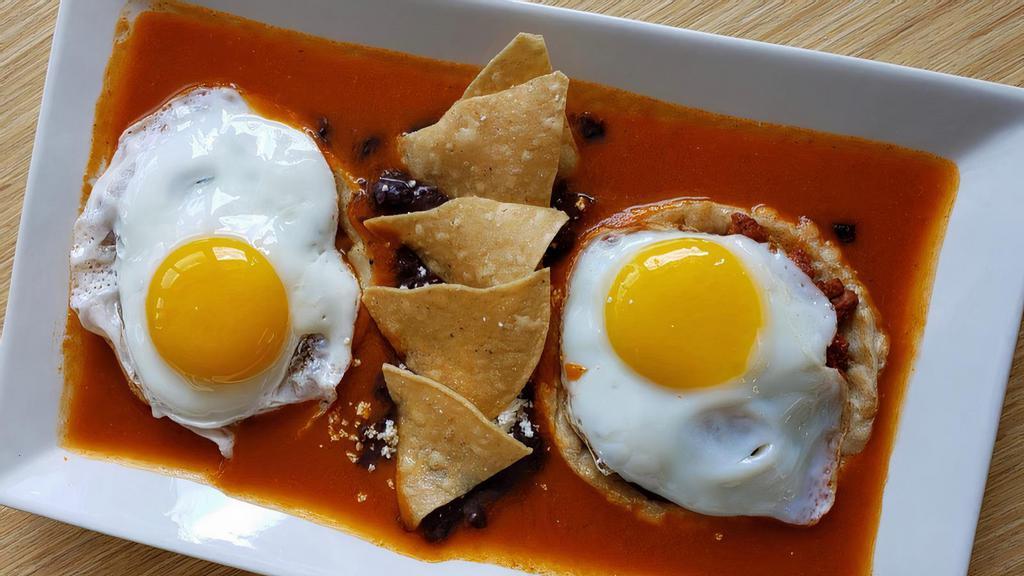 Huevos Rancheros · 2 soft tortillas topped with refried beans, sunny side eggs, salsa ranchera, queso fresco, sour cream, a slice of chorizo.