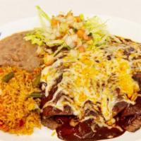 Enchiladas De Mole Poblano · Corn tortillas filled with pork carnitas, topped with mole salsa, and melted cheese, accompa...