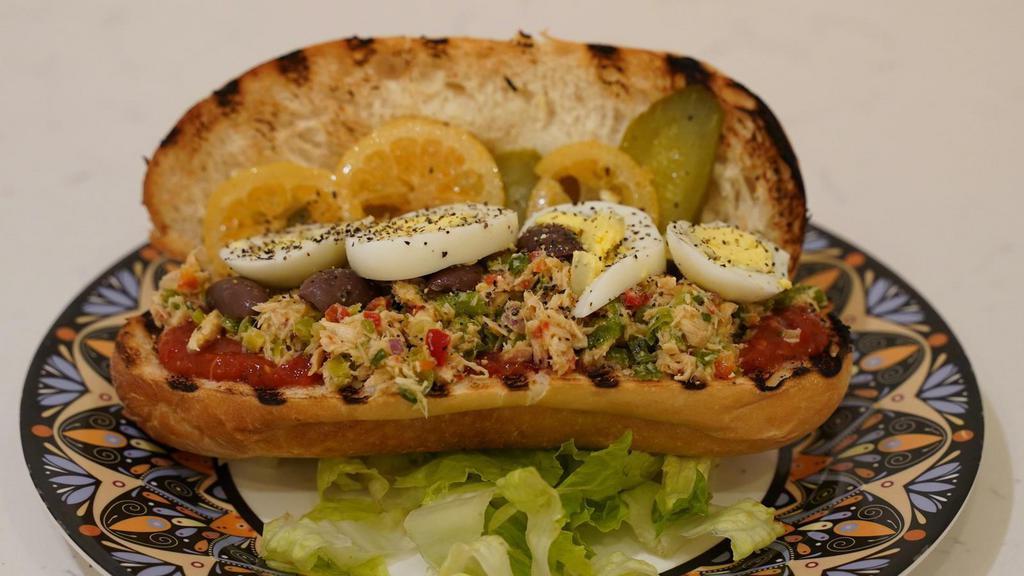 Tunisian Sandwich · Tuna, potato, boiled egg, pickles, olives, pickled lemon, in a baguette, with harissa on the side.