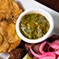 Masita De Puerco · Crispy, marinated, deep fried pieces of pork, topped with cebolitas. Served with tostones & ...