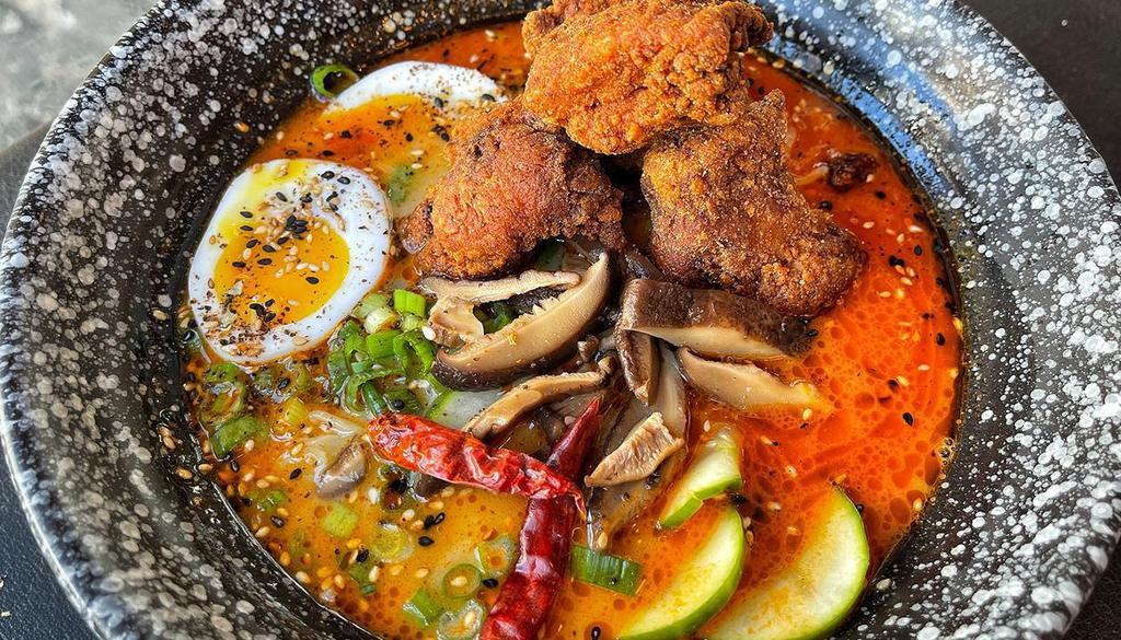 Tan Tan Spicy Ramen • · Spicy Sesame Broth, Crispy Chicken, Shiitake Mushrooms, Soft Egg, Pickled Cucumbers, Scallions, Sesame Seeds, Spicy Chili Peppers, & Spicy Chili Oil.