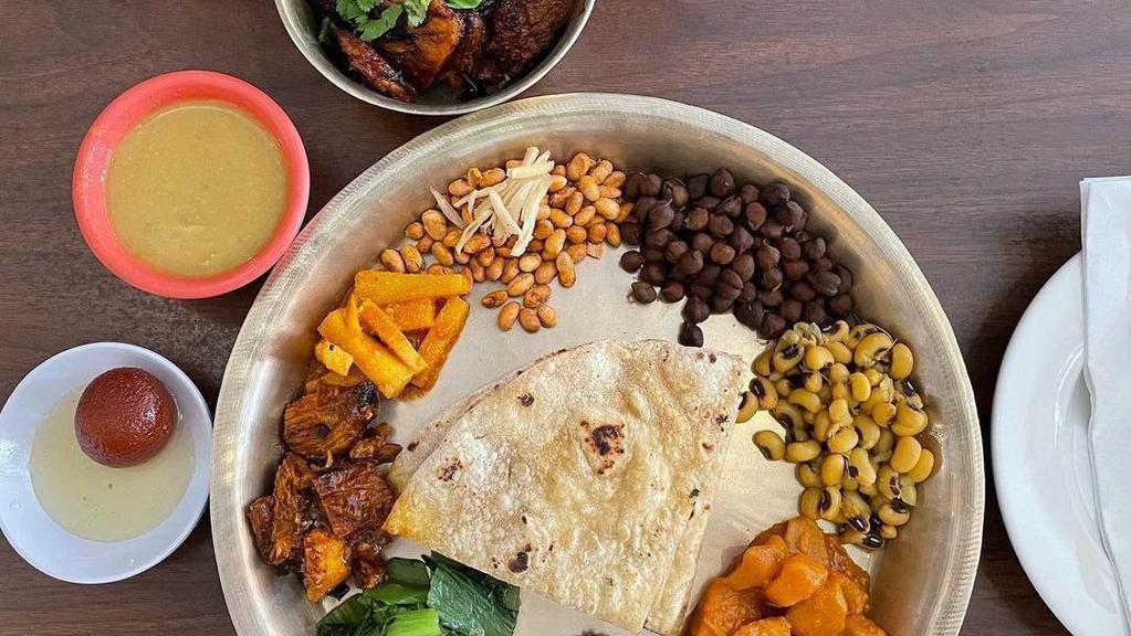 Newari Thali (Traditional Newari Feast) · Traditional Newari set consisting of beaten rice or rice of your choice, Choila, black eyed peas, chickpeas, roasted soybeans, potato pickle, mustard green, side of aloo tama soup, sweets, and curry of your choice.