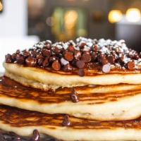 Chocolate Chip Pancakes · 3 pancakes stuffed and topped with chocolate chips. garnished with powdered sugar.