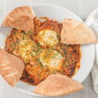 Shakshuka · Poached eggs in a Mediterranean tomato sauce with pita and salad.