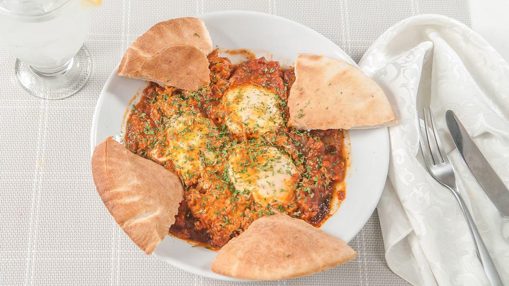 Shakshuka · Poached eggs in a Mediterranean tomato sauce with pita and salad.