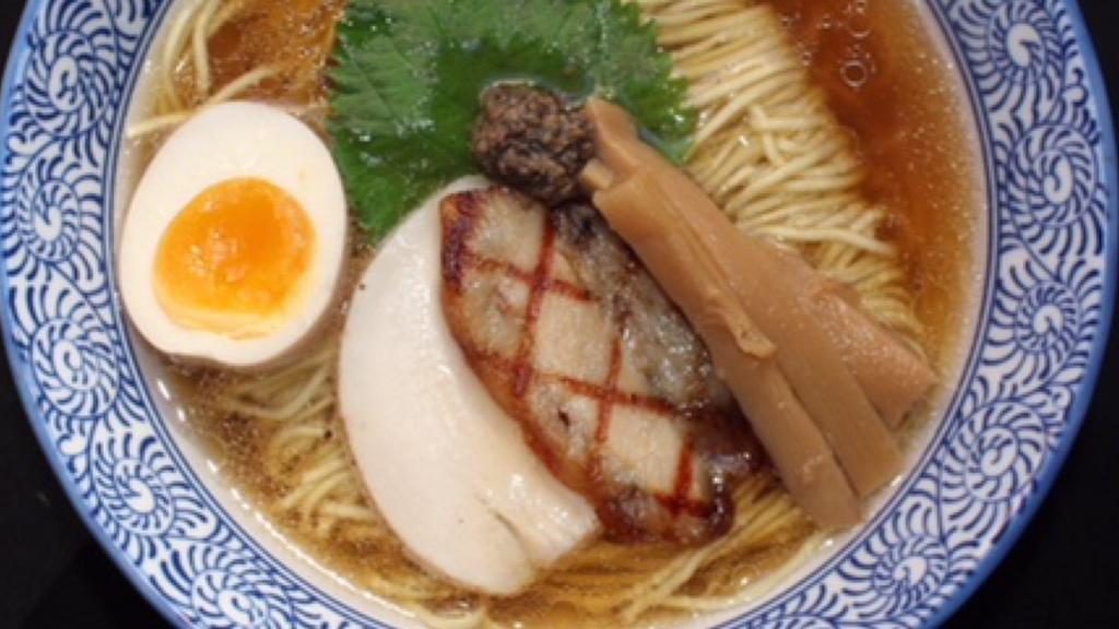 New Tokyo Style Shoyu Ramen · Dark savory chicken truffle and porcini broth with thin flour noodles and topped with grilled chaahu pork belly, chicken breast, marinated bamboo shoots, shiso, soft boiled egg, mushroom paste, and pork fat.