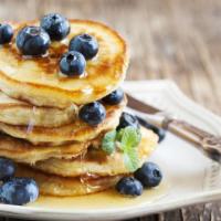 Buttermilk Pancakes With Fresh Blueberries · 3 fluffy golden pancakes topped with fresh blueberries and served with a side of syrup and b...