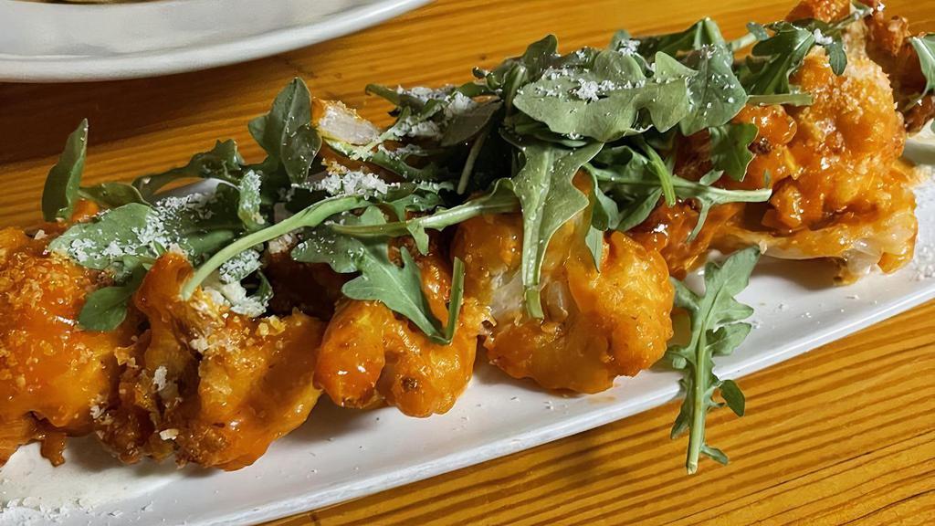 Buffalo Cauliflower · Beer-battered cauliflower tossed in buffalo sauce over house-made blue cheese dressing topped with arugula and parmesan cheese.
